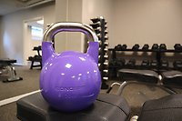 En lila kettlebell med del av gymmet i bakgrunden.